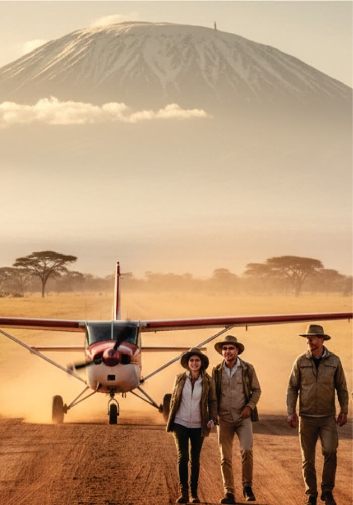 Three people standing in front of a small airplane with a mountain in the background