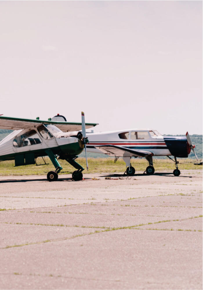 Two small airplanes on a runway with a clear sky.