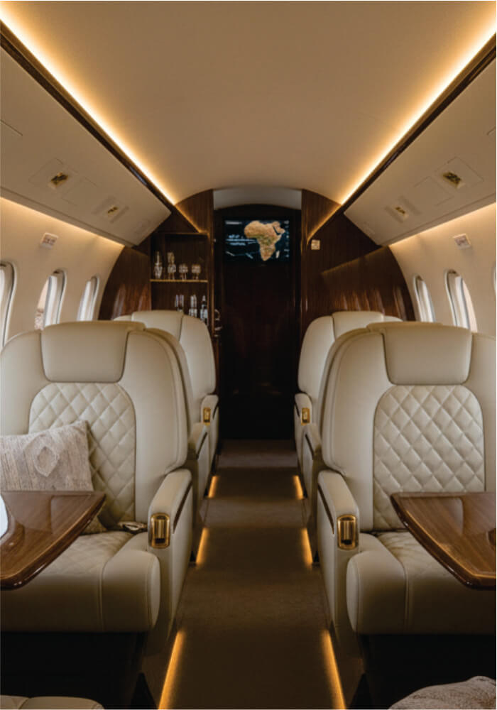 Luxury airplane interior with beige leather seats and wooden tables.
