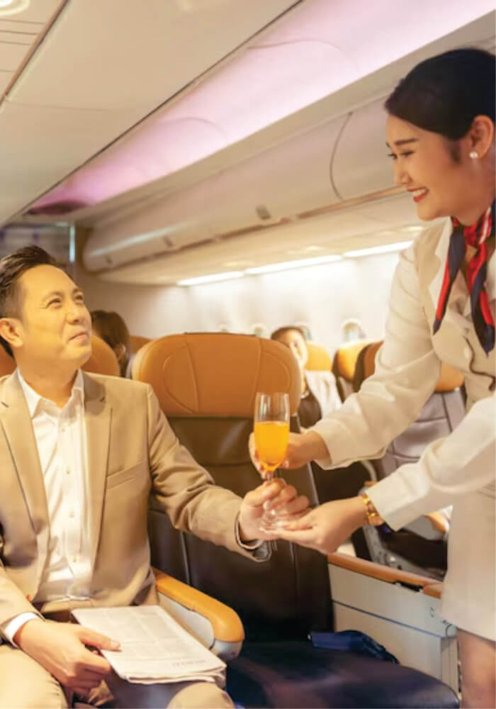 A flight attendant serves a drink to a businessman on a corporate aircraft on budget jet charter fly-in Safari Masai Mara from Nairobi