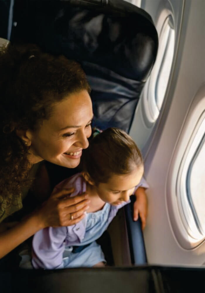 Smiling mom and her little kid looking at the scenery outside the plane window on luxury fly in safari for family in Kenya