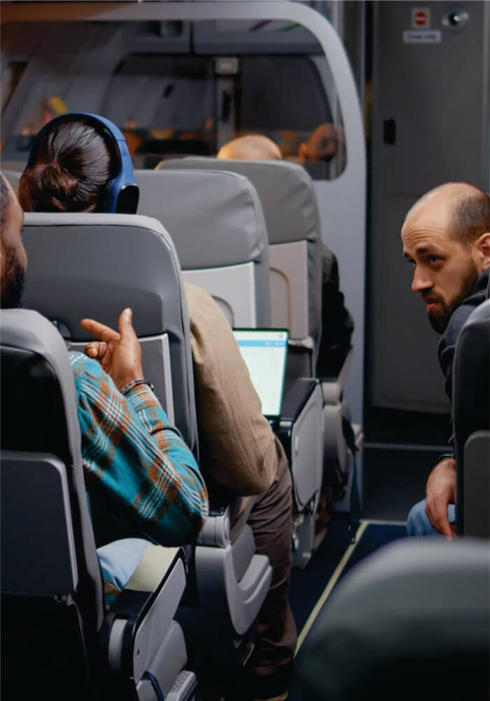 Passengers on an airplane with one person using a laptop.