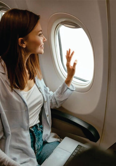 Cheerful black woman looking out the window in airplane on affordable Masai Mara fly-in safari 3 days package in Kenya