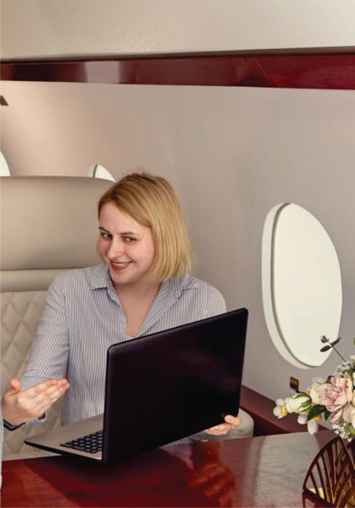 Young woman using laptop computer on airplane on a short 4-day Budget Luxury Nairobi Fly in Safari Masai Mara package